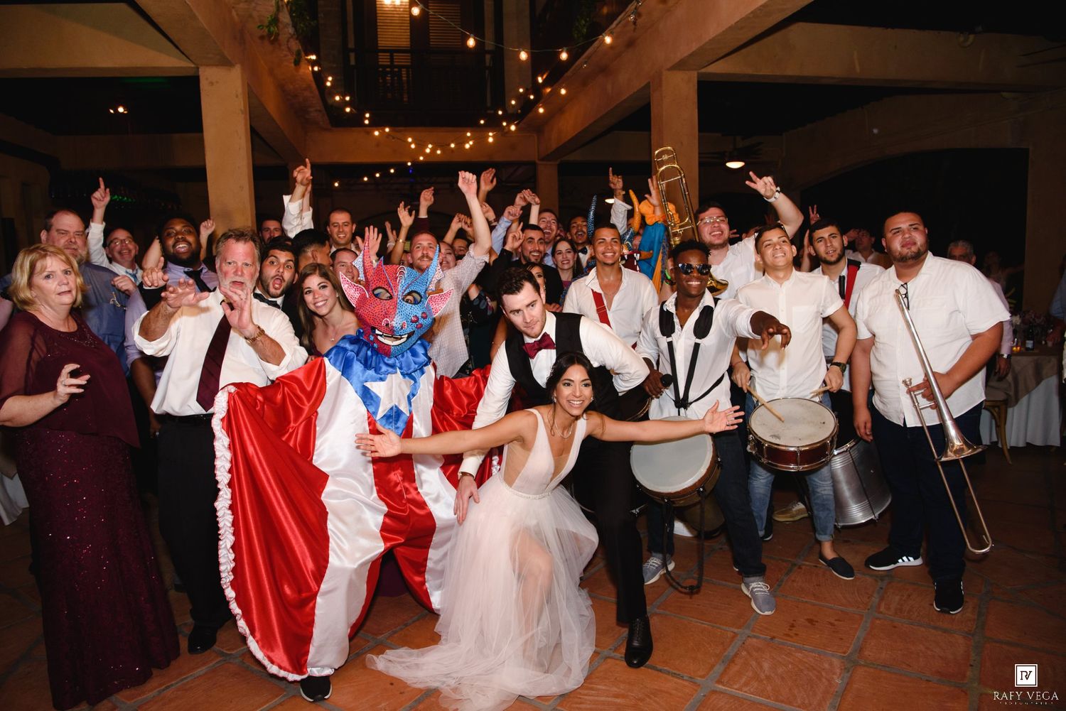 Joyful wedding reception with bride, groom, and guests celebrating alongside a festive band in elegant venue.