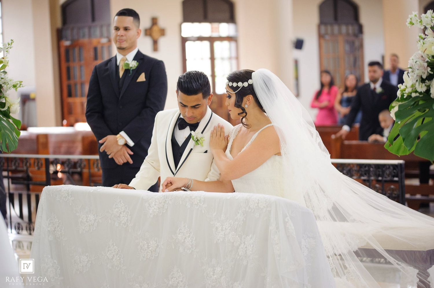 Bride and groom signing wedding documents at church altar in elegant white attire during formal ceremony.