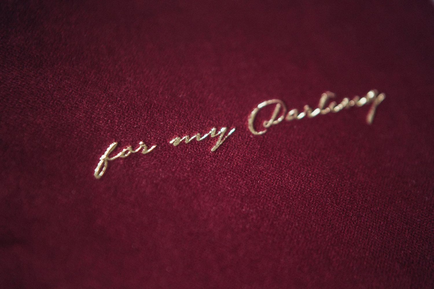 Gold cursive embroidery reading 'for my Darling' on luxurious dark red velvet fabric.