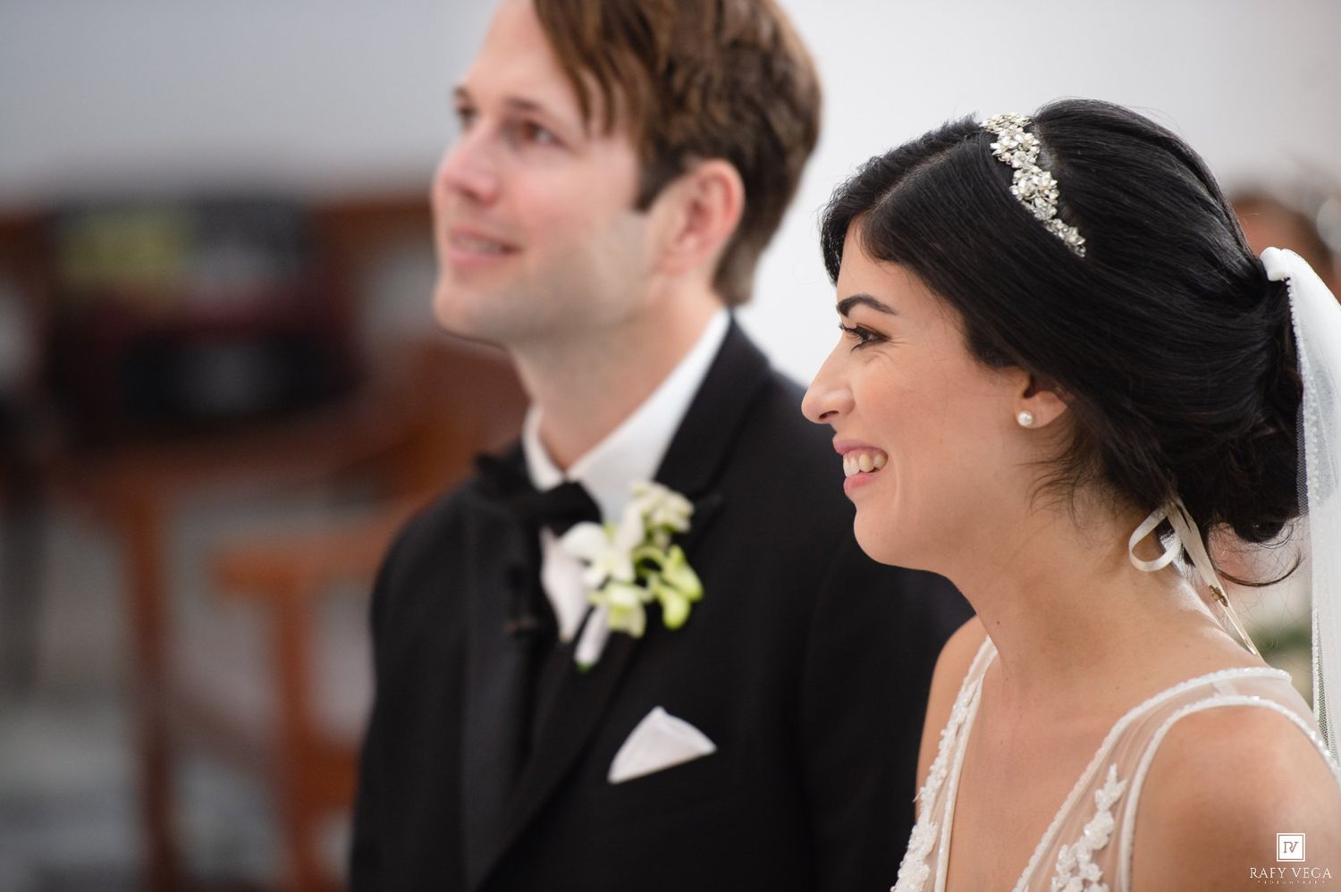 A smiling bride and groom in wedding attire share a joyful moment during their ceremony.