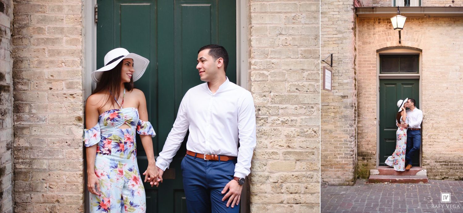 Couple holding hands smiling at each other in front of a green door in a charming European-style courtyard.