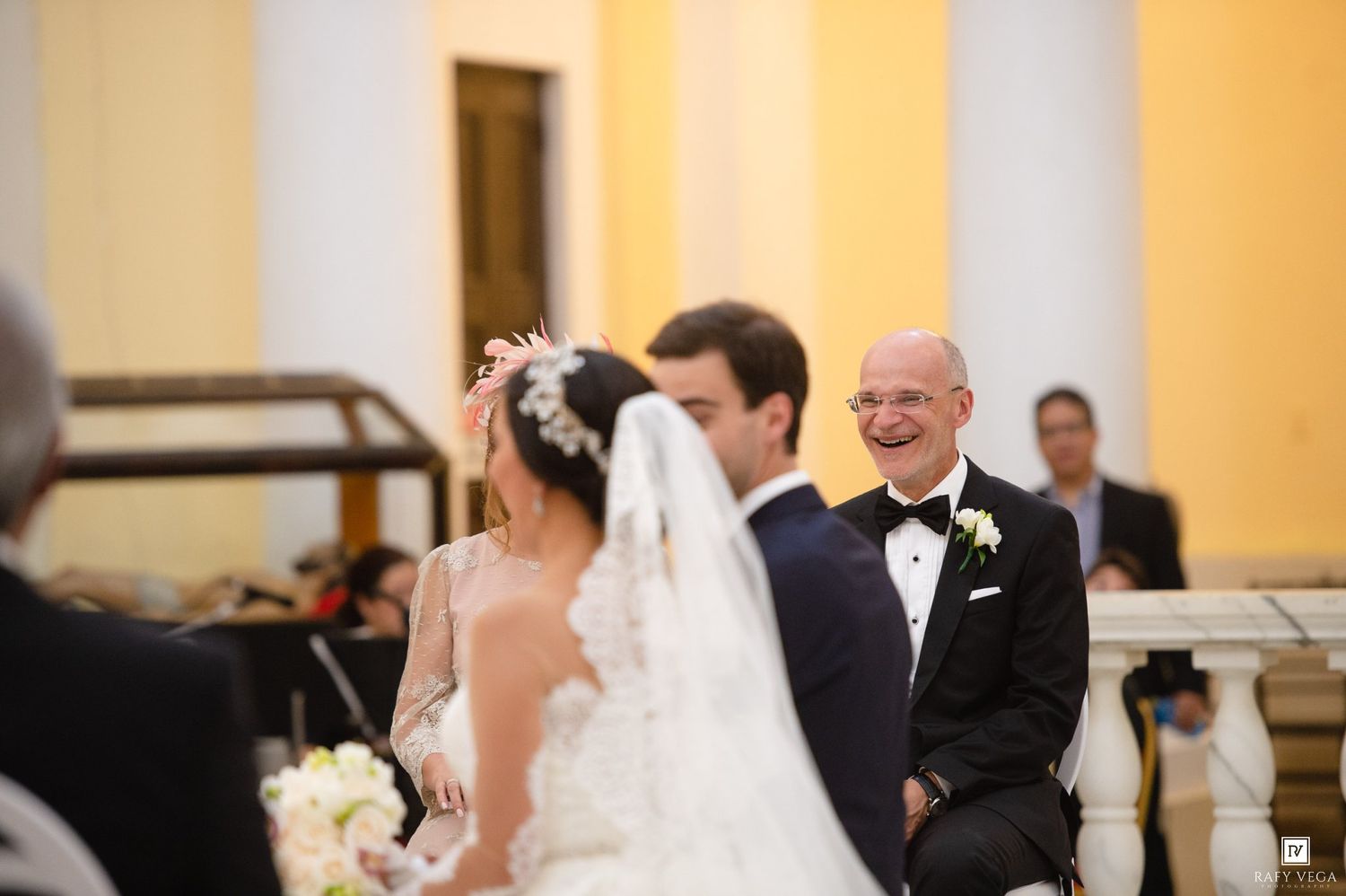 Smiling officiant watches bride and groom exchange vows at elegant church wedding altar ceremony.
