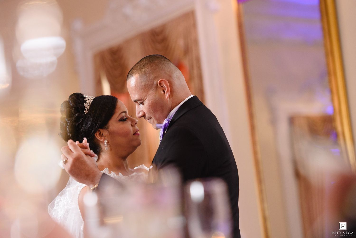 A bride and groom share an intimate first dance moment at an elegant wedding reception venue.