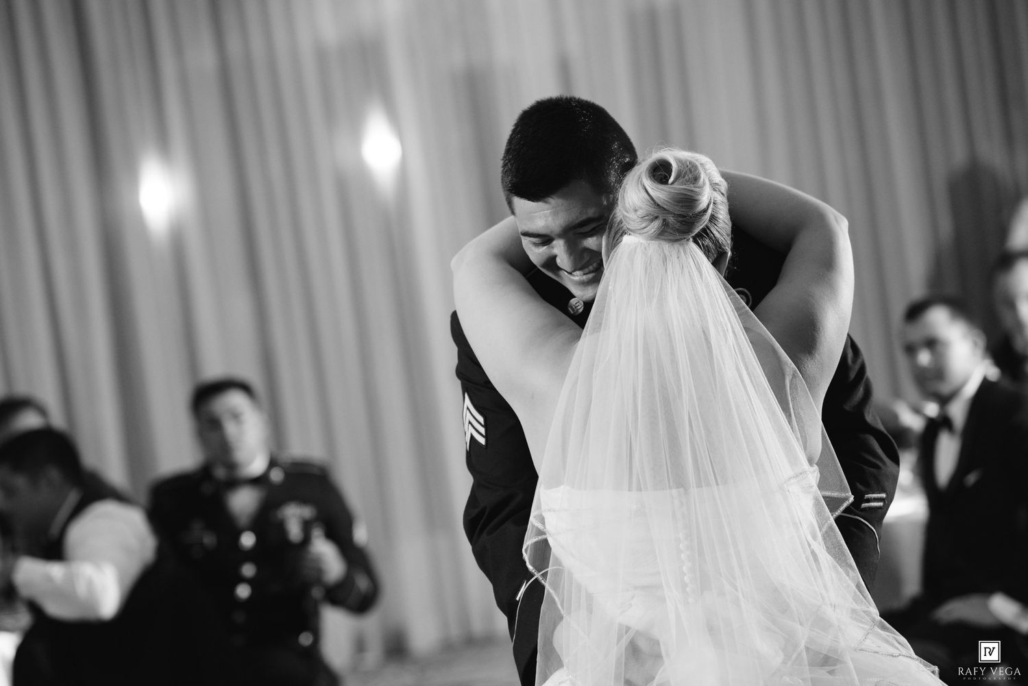 Black and white photo of a groom in military uniform dipping his bride during their first wedding dance.