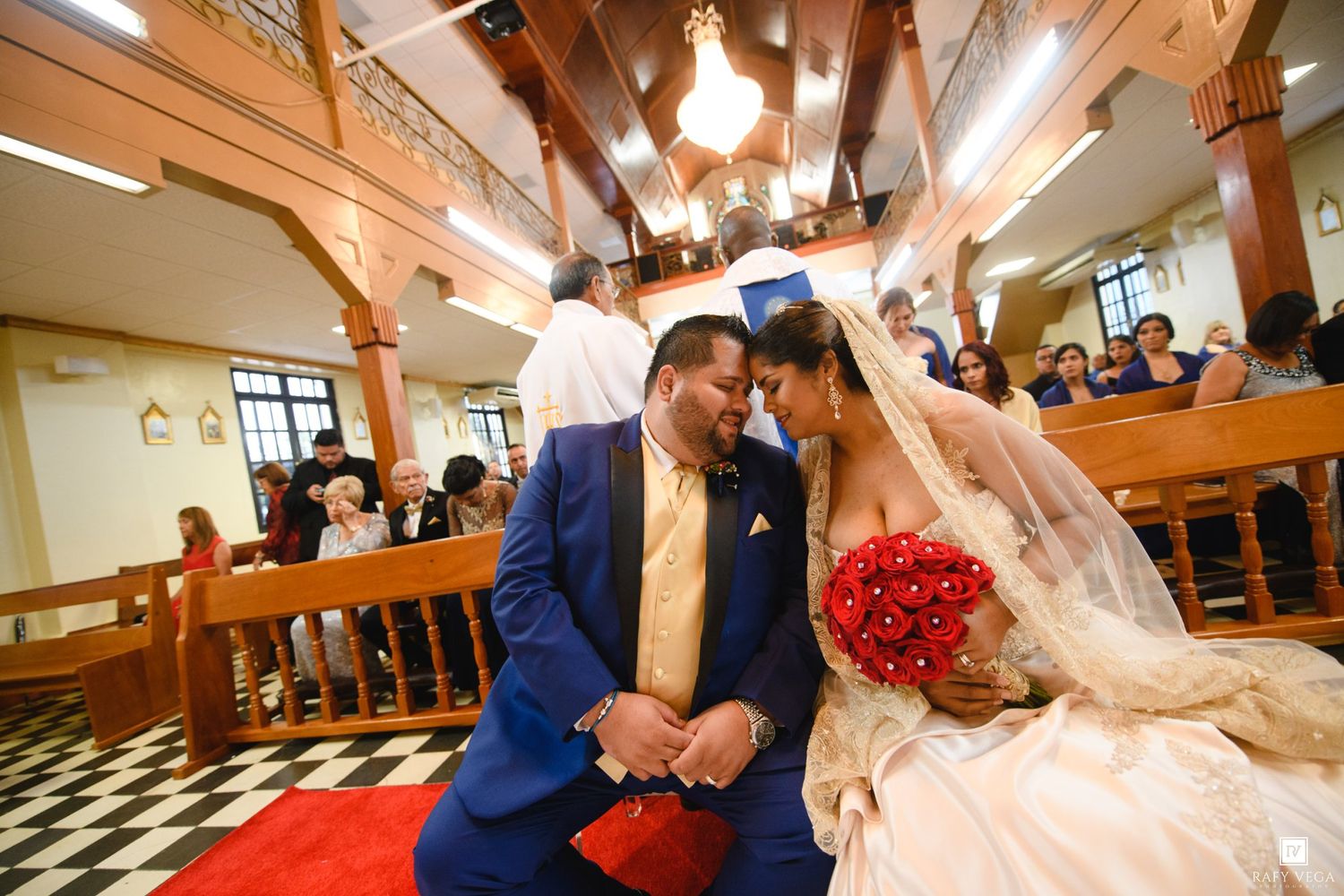 A bride and groom share an intimate moment kneeling together at the altar during their church wedding ceremony.