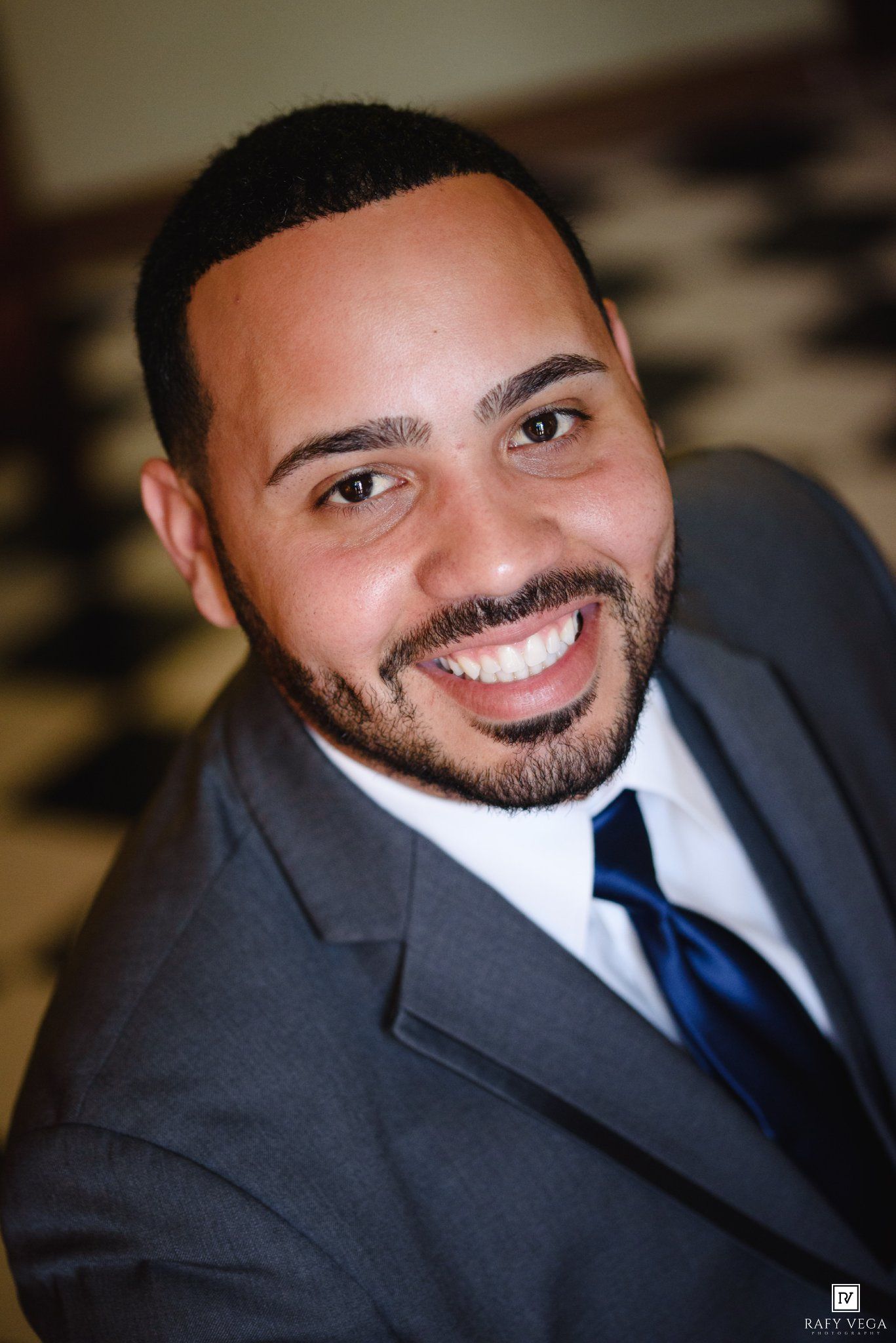 Smiling man in gray suit and blue tie poses for professional portrait photo.