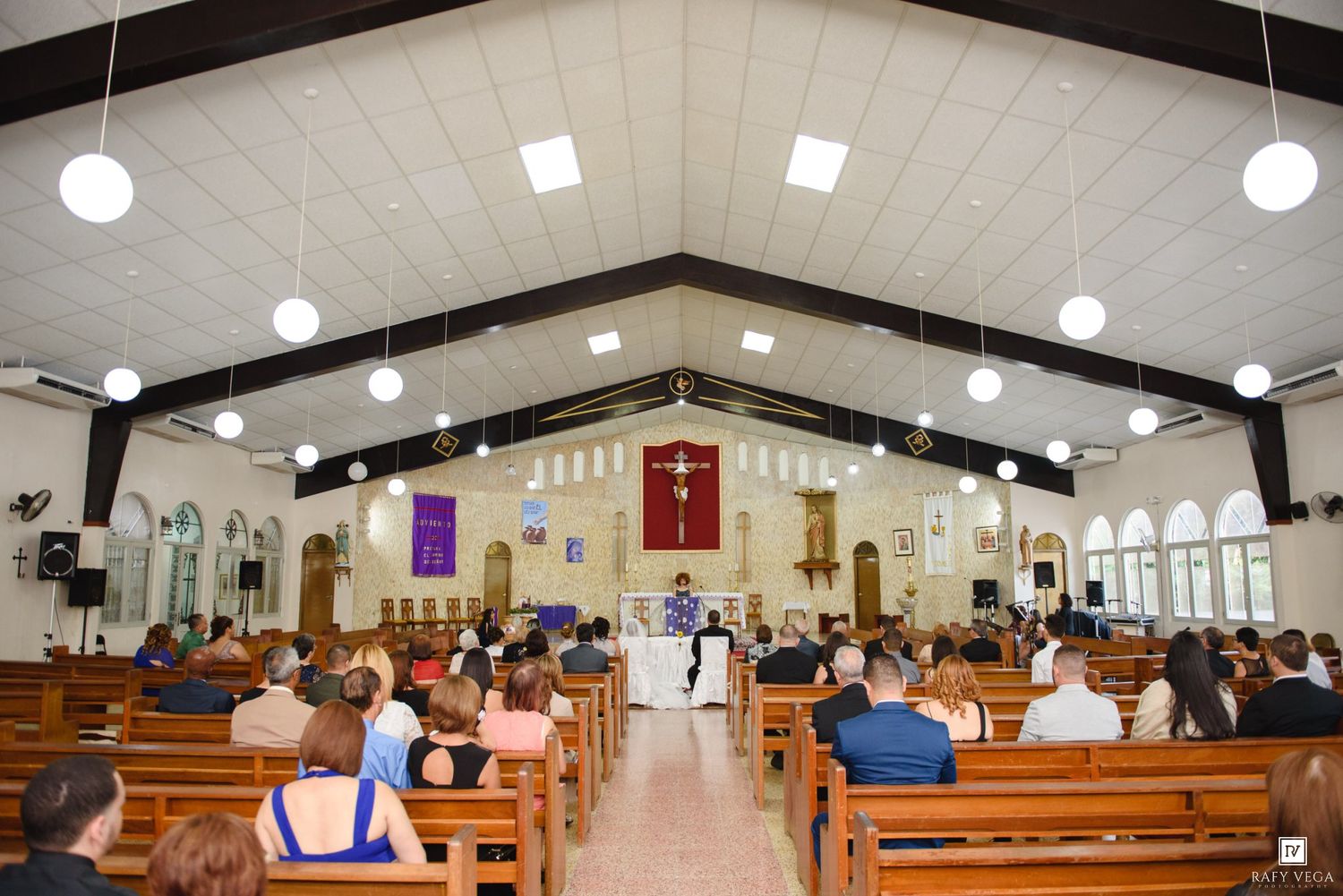 Wedding ceremony in a traditional church with guests seated in wooden pews facing the altar.