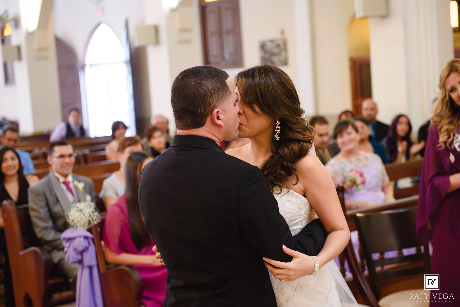 Bride and groom sharing their first kiss during a romantic church wedding ceremony.