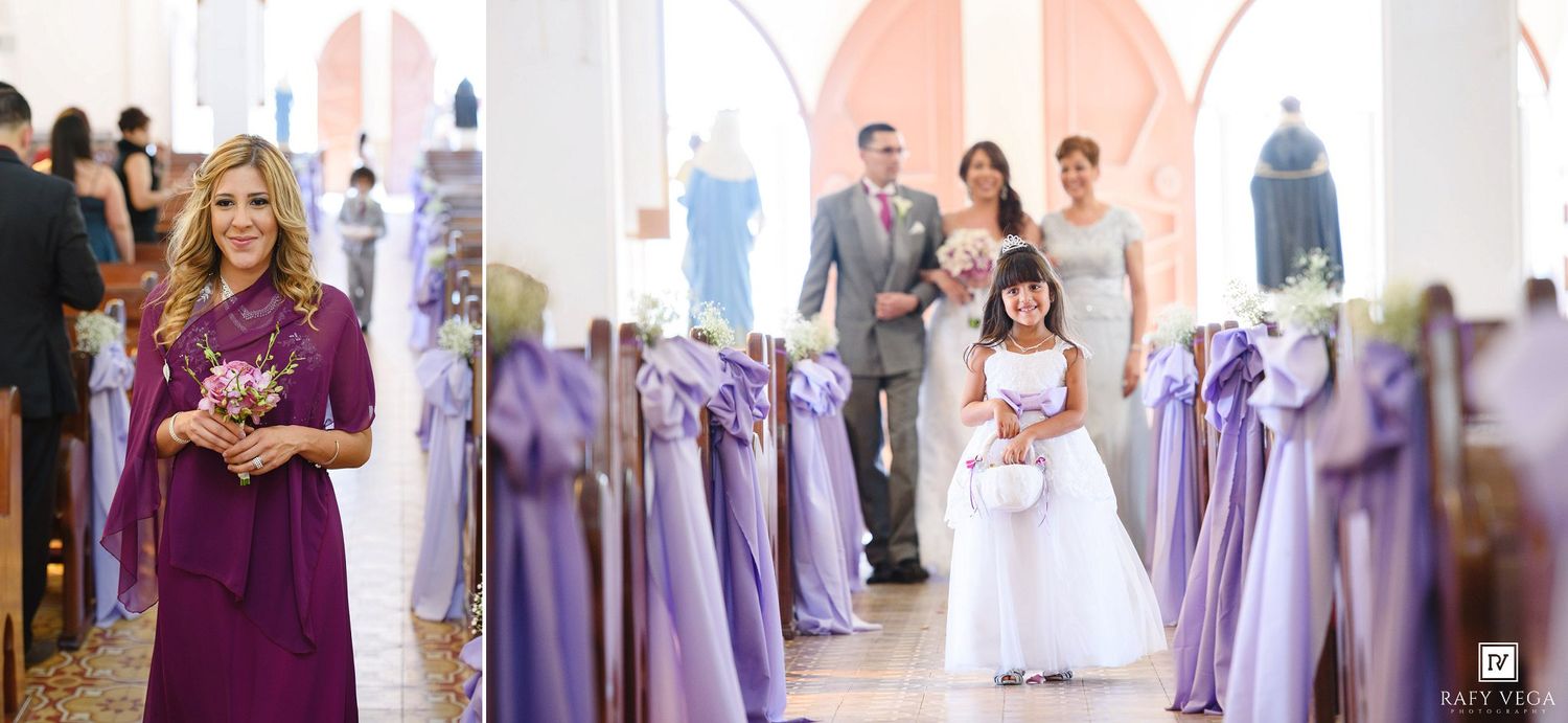 Wedding ceremony procession down church aisle decorated with purple ribbon bows on pews.