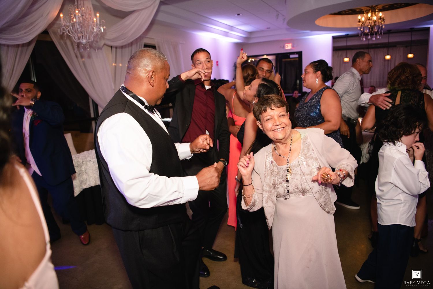 Guests dancing and celebrating at a formal wedding reception in a decorated ballroom venue.