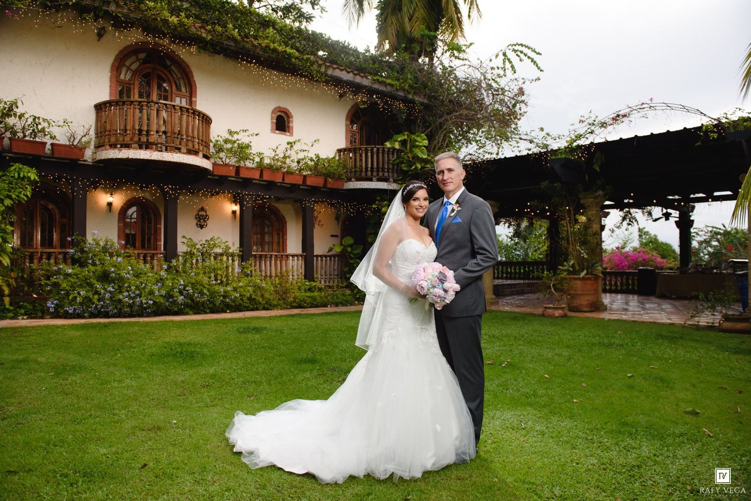 Bride and groom posing in front of a beautiful hacienda venue on their wedding day.