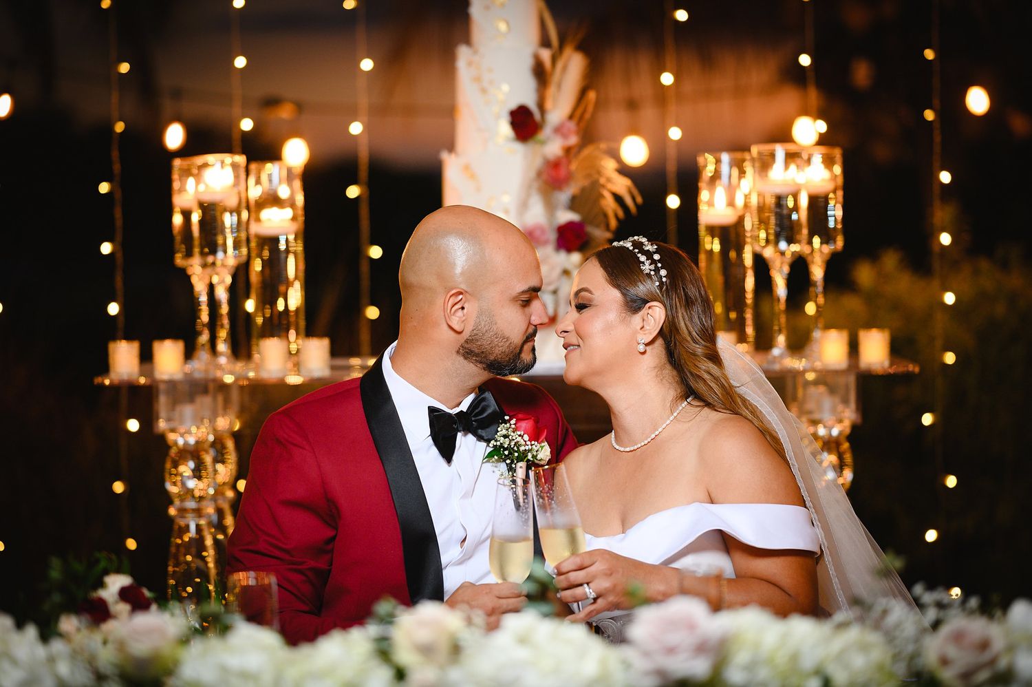 Bride and groom share a romantic moment at their elegant wedding reception with candles and fairy lights.