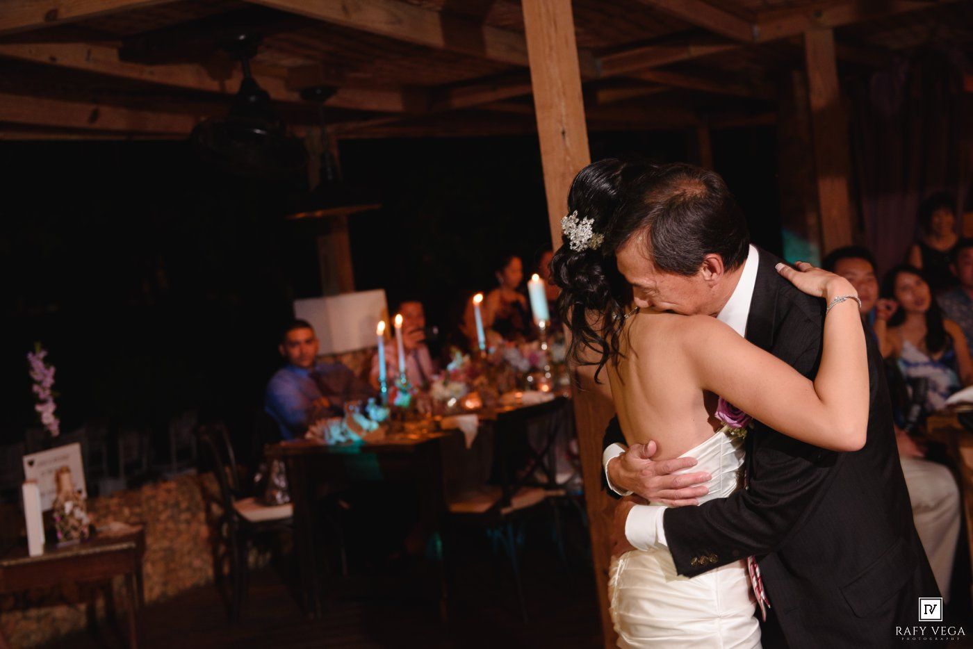 Couple shares intimate first dance embrace at candlelit wedding reception.