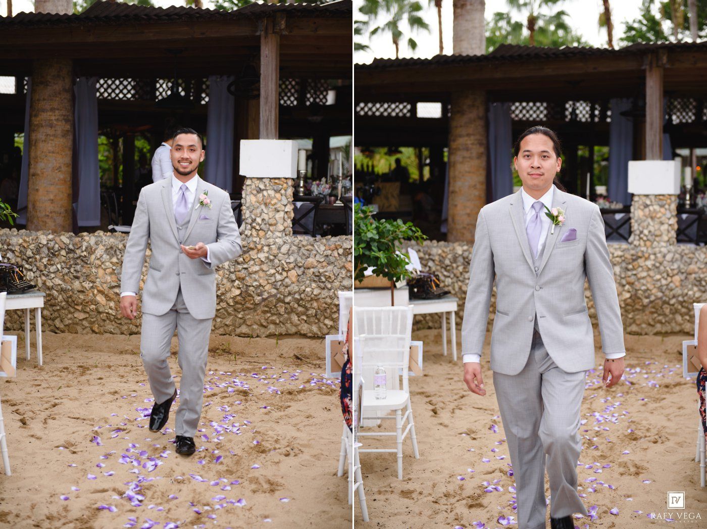 Two groomsmen in gray suits walking down beach wedding aisle with purple floral decor.