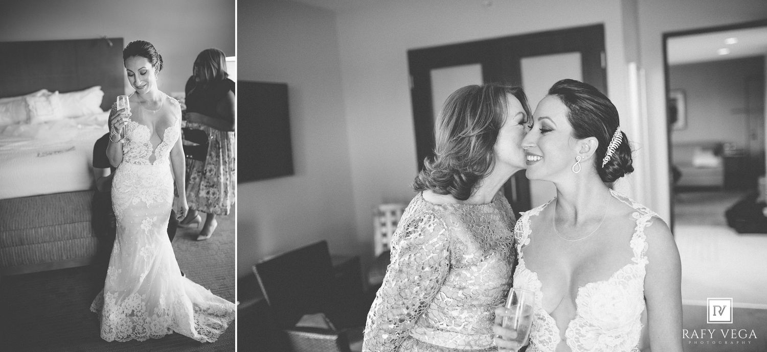 Black and white photo of a bride in lace gown with her mother sharing a tender moment before the wedding ceremony.
