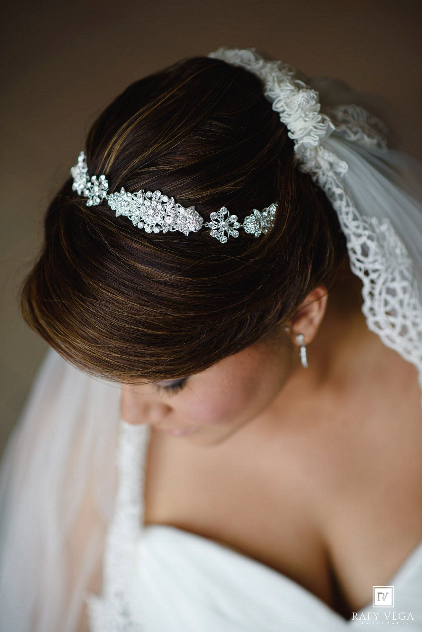 Elegant bridal updo with pearl and crystal hair vine accessory and lace veil on brunette bride.
