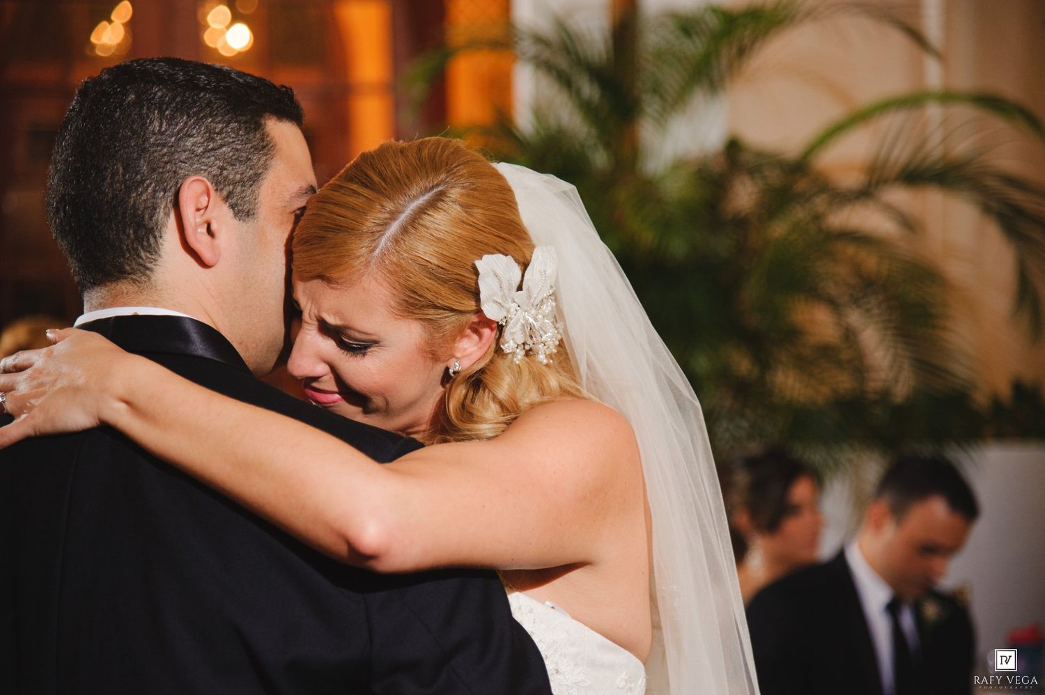 Bride and groom share an emotional first dance embrace at elegant wedding reception.