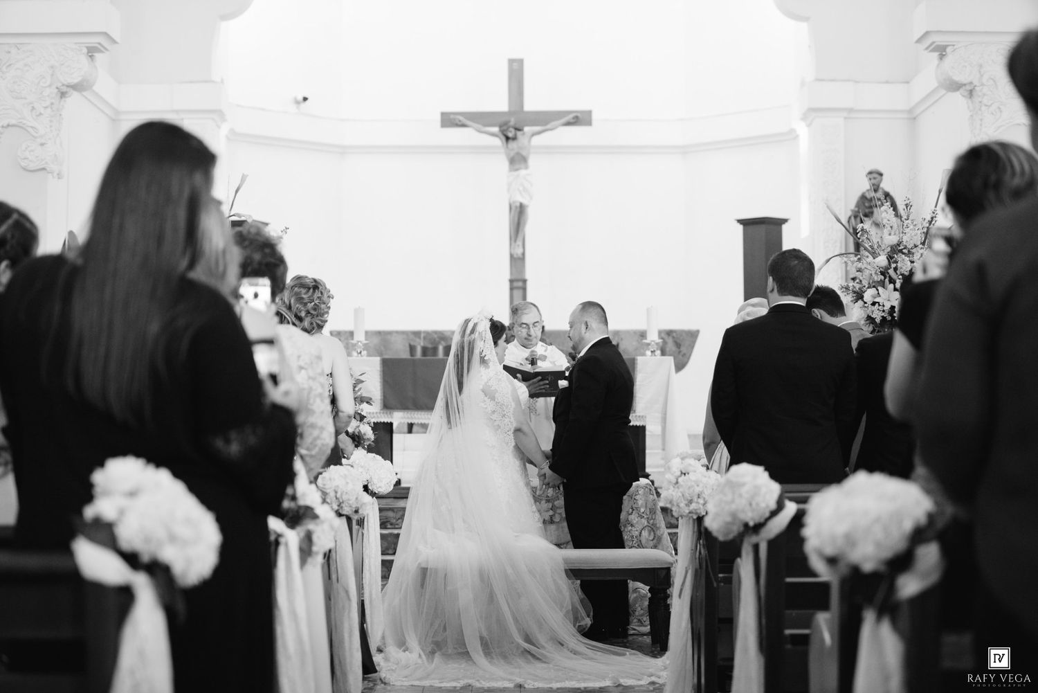 Black and white photo of a bride and groom at the altar of a church during their wedding ceremony.