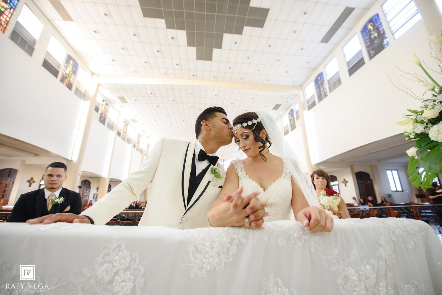 A groom kisses his bride at the altar during a beautiful church wedding ceremony.