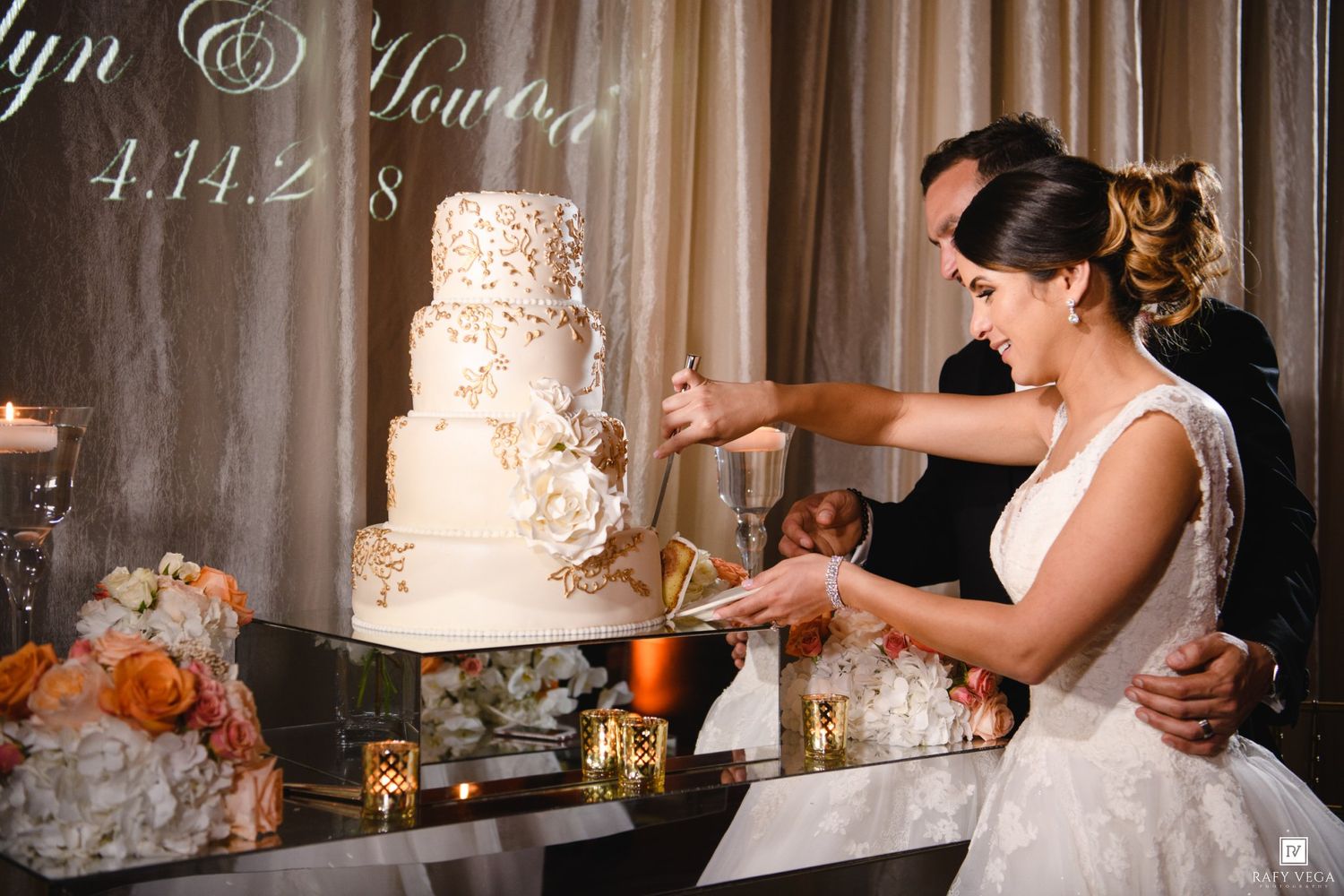 Bride and groom cutting a white and gold tiered wedding cake at their elegant reception.