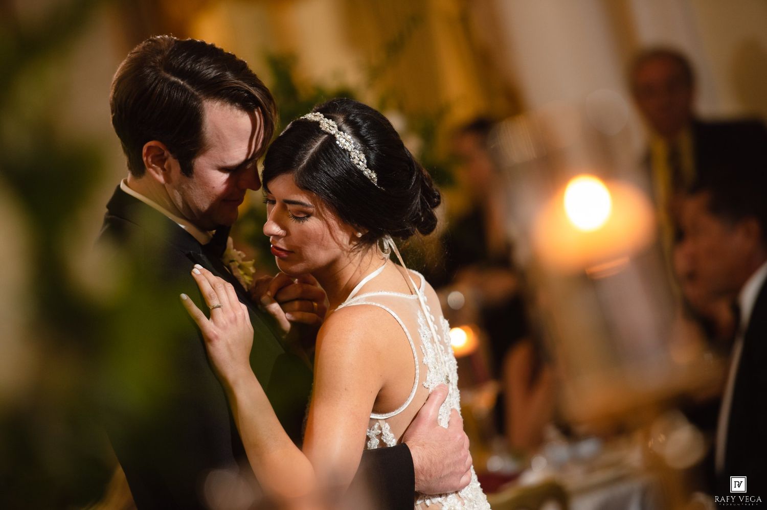 Bride and groom share intimate first dance at romantic candlelit wedding reception.