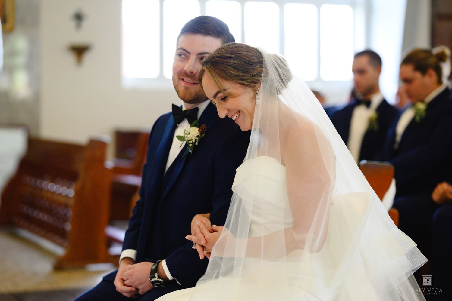 A joyful bride and groom share a laugh while seated together during their church wedding ceremony.