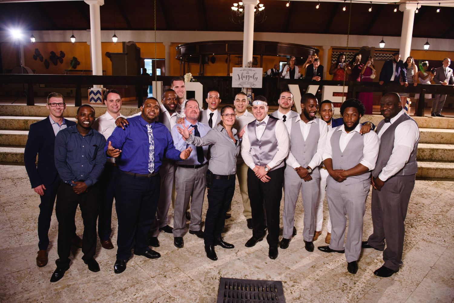 Group of men in formal attire posing together at an indoor wedding reception venue.