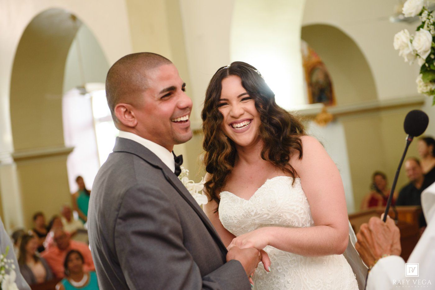 Happy bride and groom laughing together at the altar during their wedding ceremony inside a church.