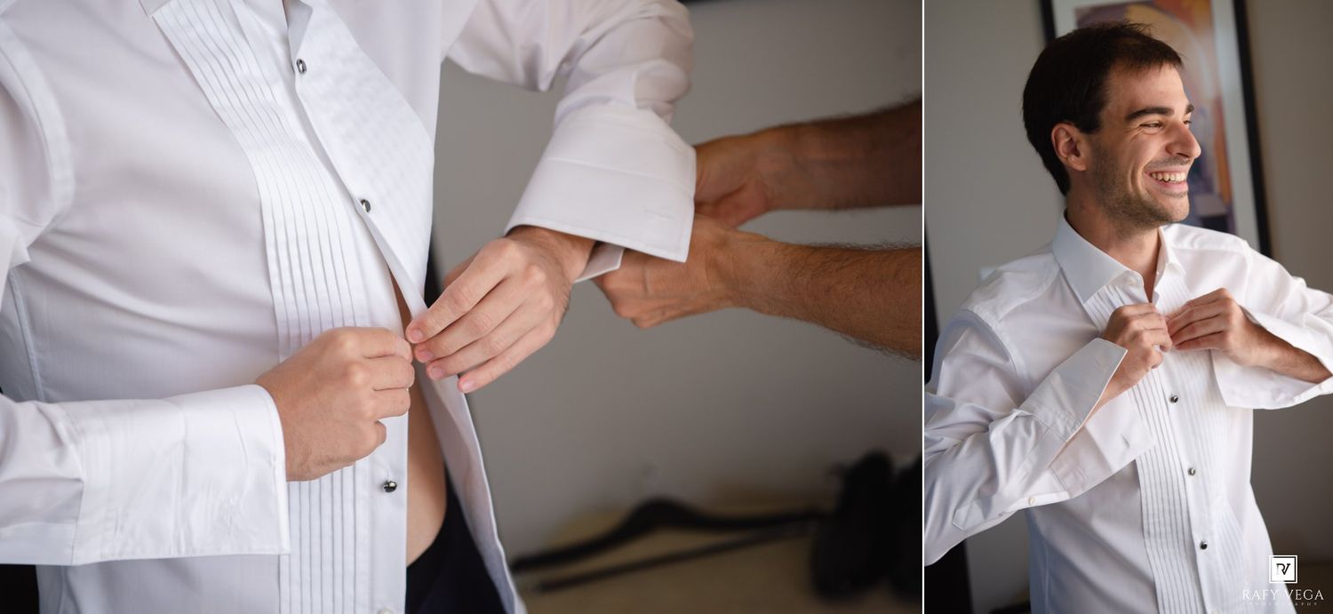 Groom in white tuxedo shirt adjusting cufflinks and tie while smiling during wedding preparation.