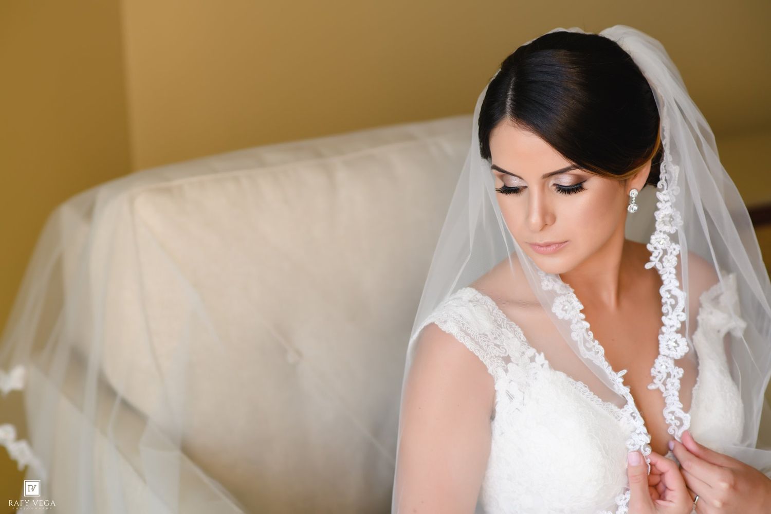 Elegant bride in lace wedding dress and veil looking down, preparing for her wedding ceremony.