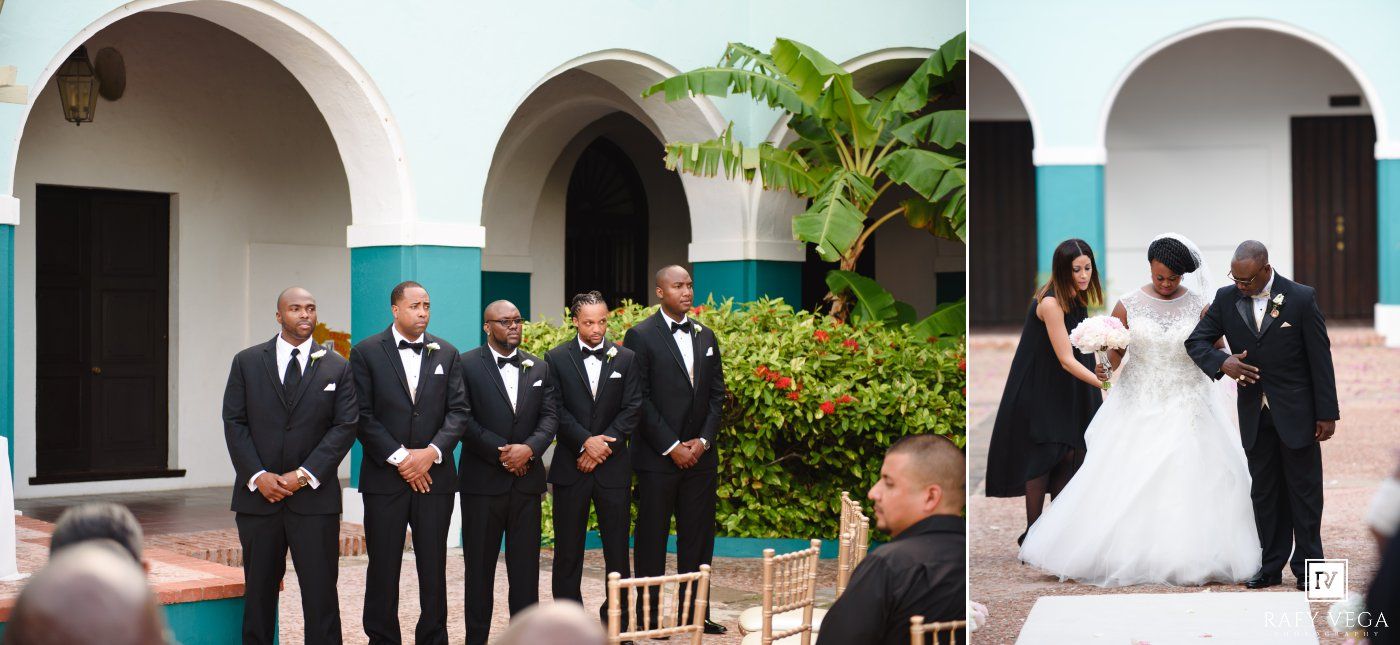 Groomsmen in black tuxedos stand with bride and groom during outdoor wedding ceremony at elegant venue.