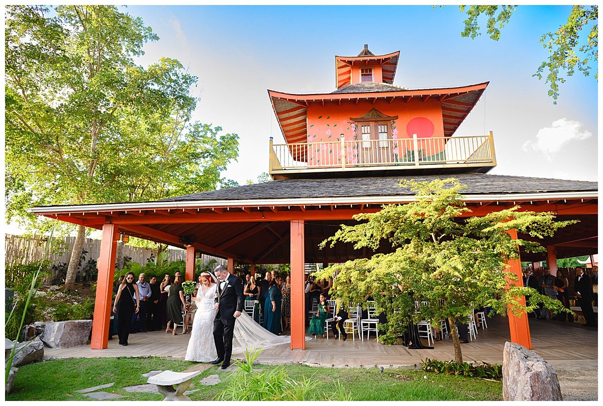 Couple shares first dance outside a stunning red Japanese pagoda wedding venue surrounded by lush greenery.