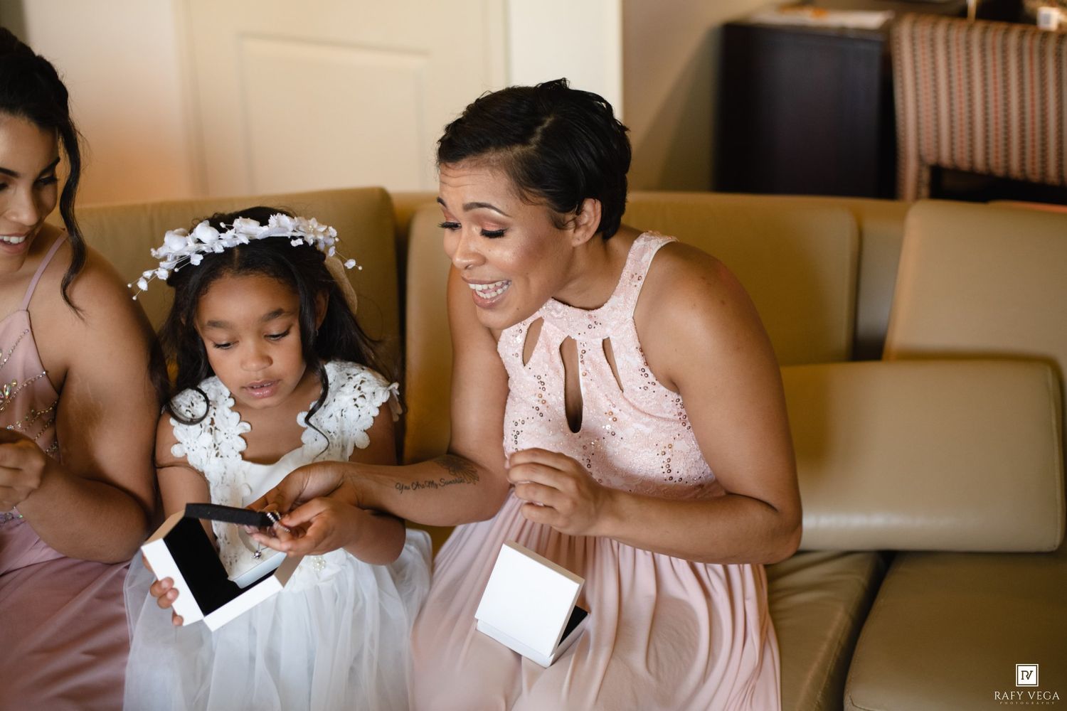 Bridesmaid in blush pink dress shares a joyful moment with flower girl in white dress at a wedding celebration.