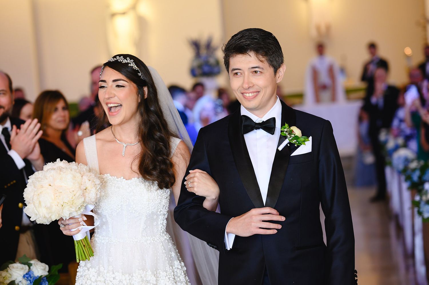 Joyful newlyweds walk down the church aisle together after their wedding ceremony.