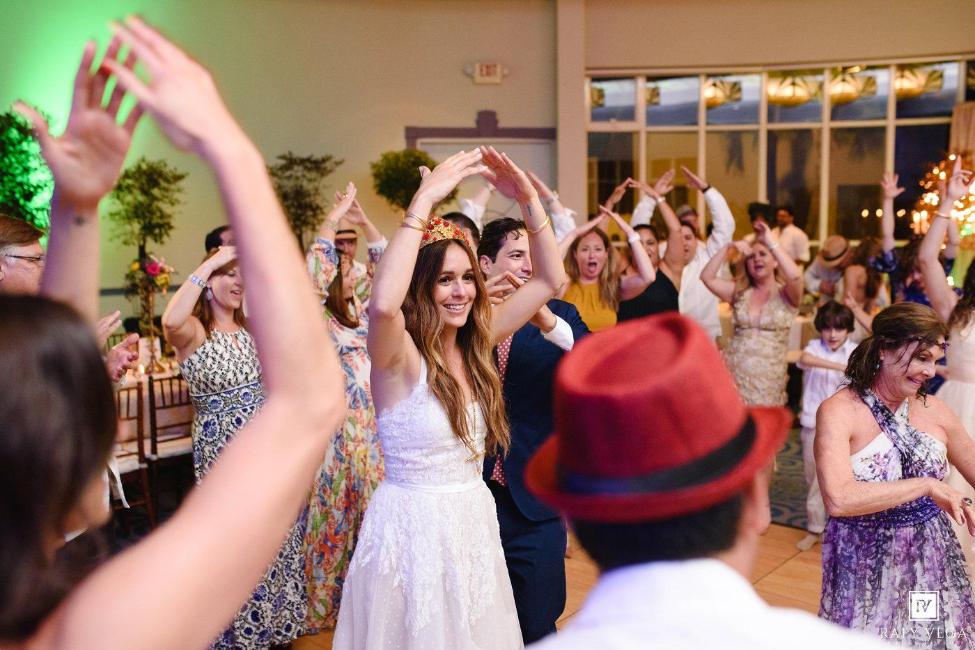 Bride and groom dancing joyfully with guests at a lively wedding reception celebration.