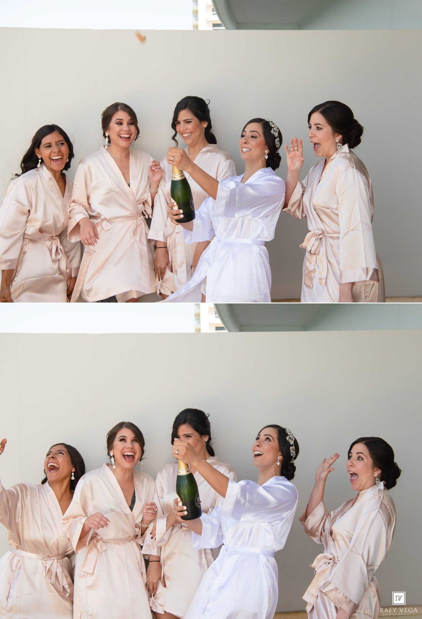Bride in white robe pops champagne with bridesmaids in blush robes during wedding preparations.