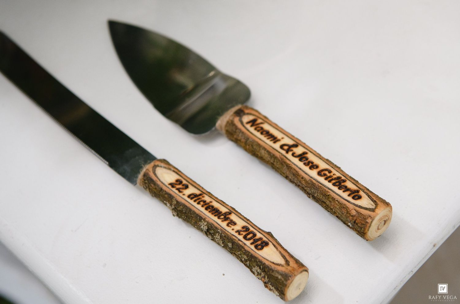 Personalized wooden handle cake cutting set with engraved names and date for a wedding ceremony.