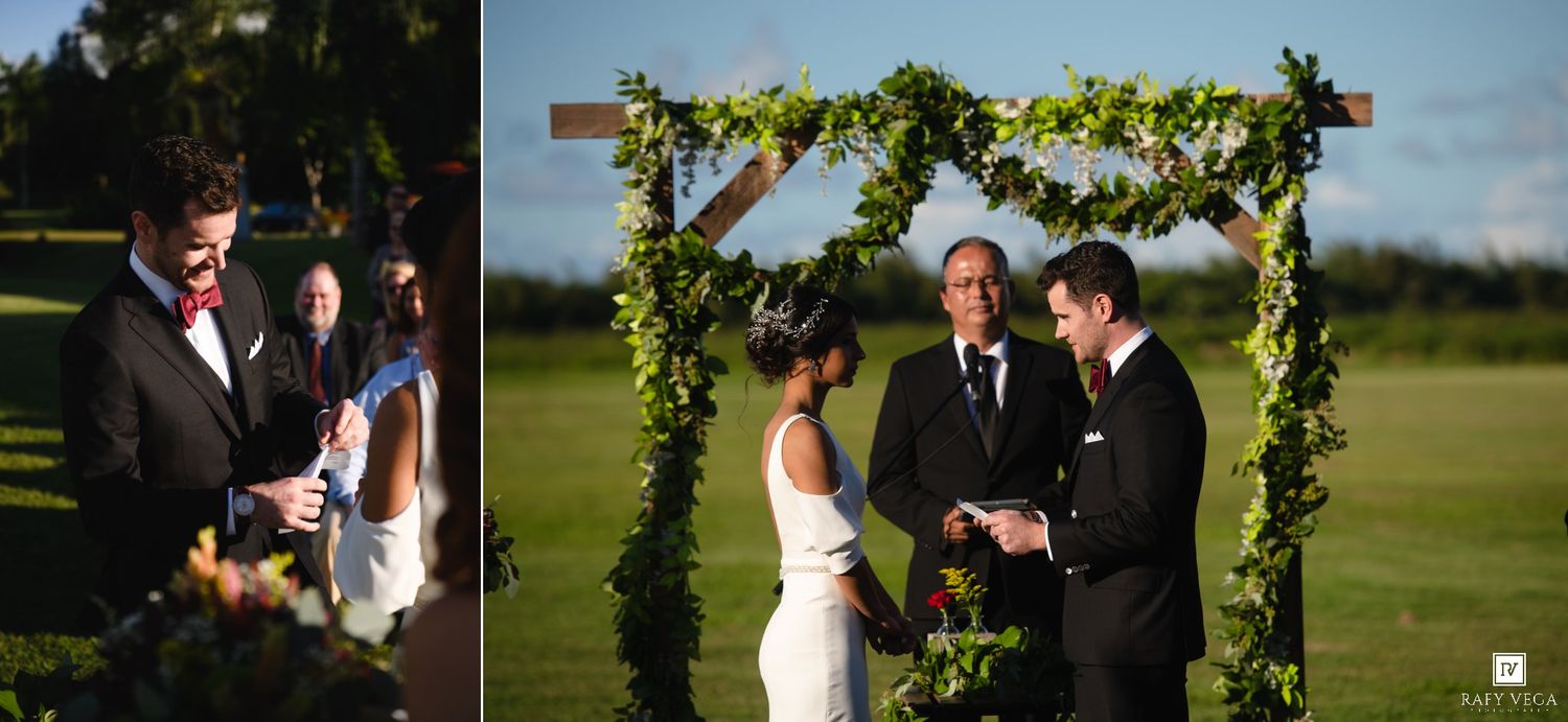 Outdoor wedding ceremony under a wooden arch adorned with greenery, bride and groom exchanging vows on a lush lawn.