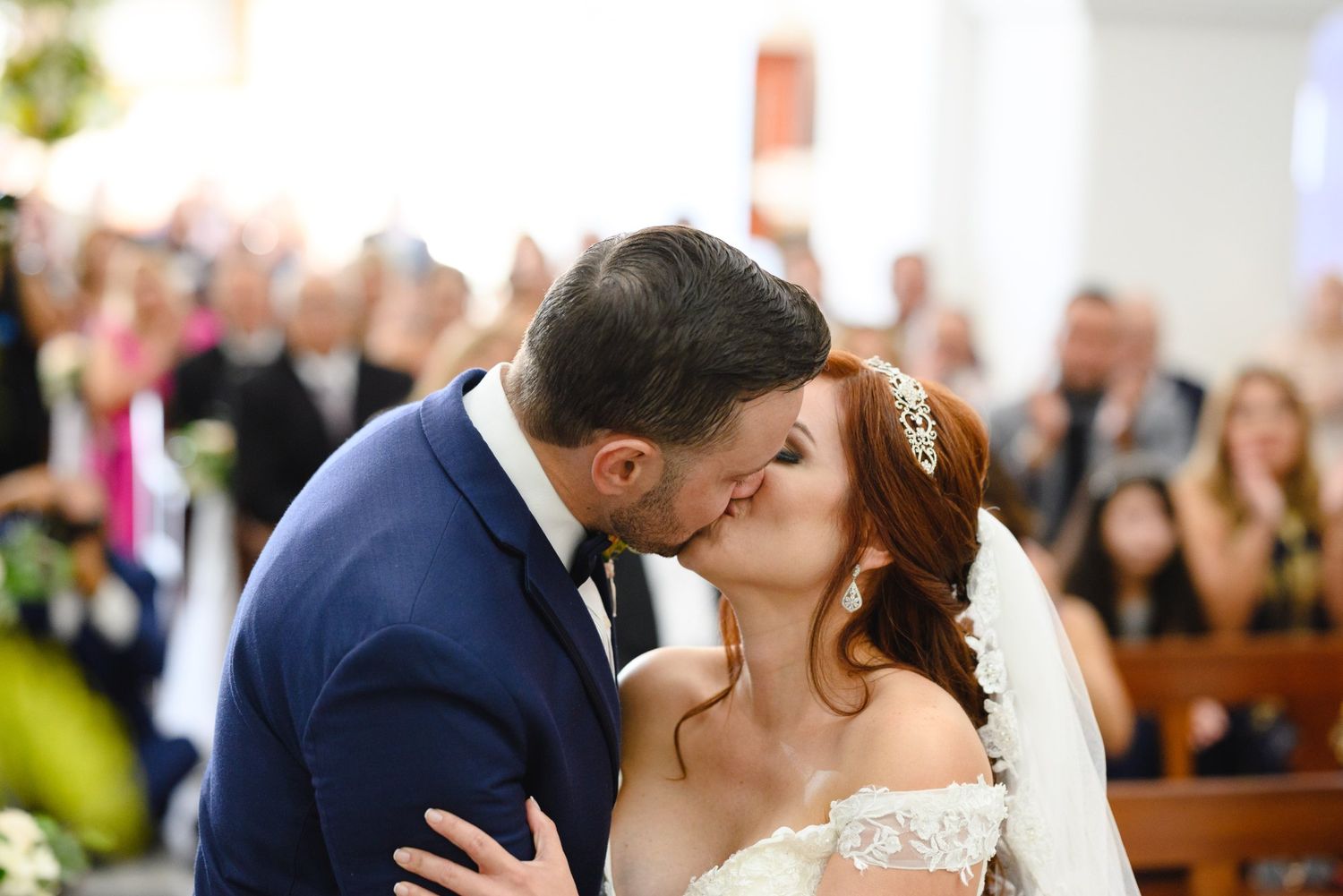Bride and groom share their first kiss at the altar during a romantic church wedding ceremony.