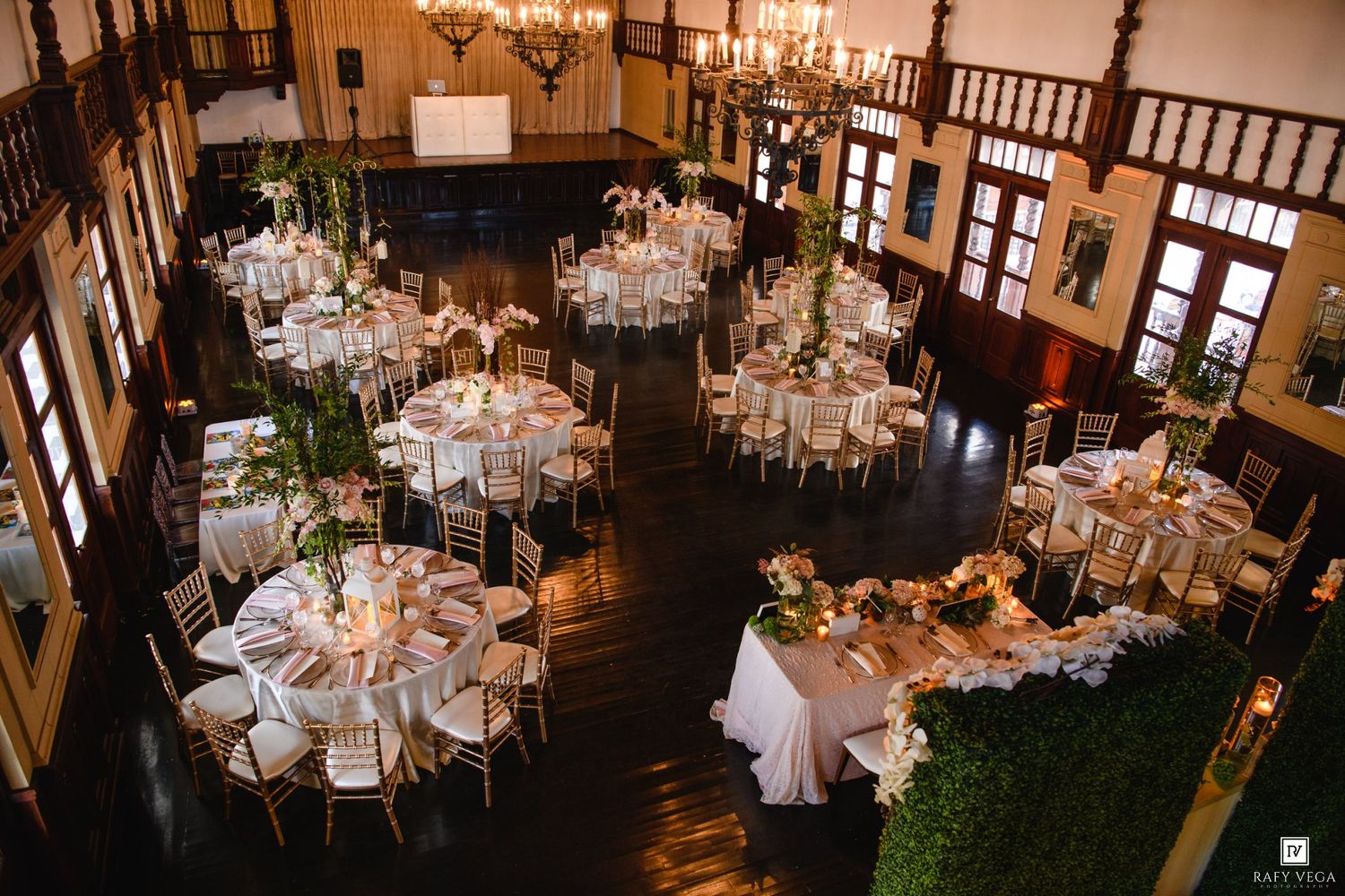 Aerial view of elegant wedding reception hall with round tables, white linens, and floral centerpieces in a historic venue.