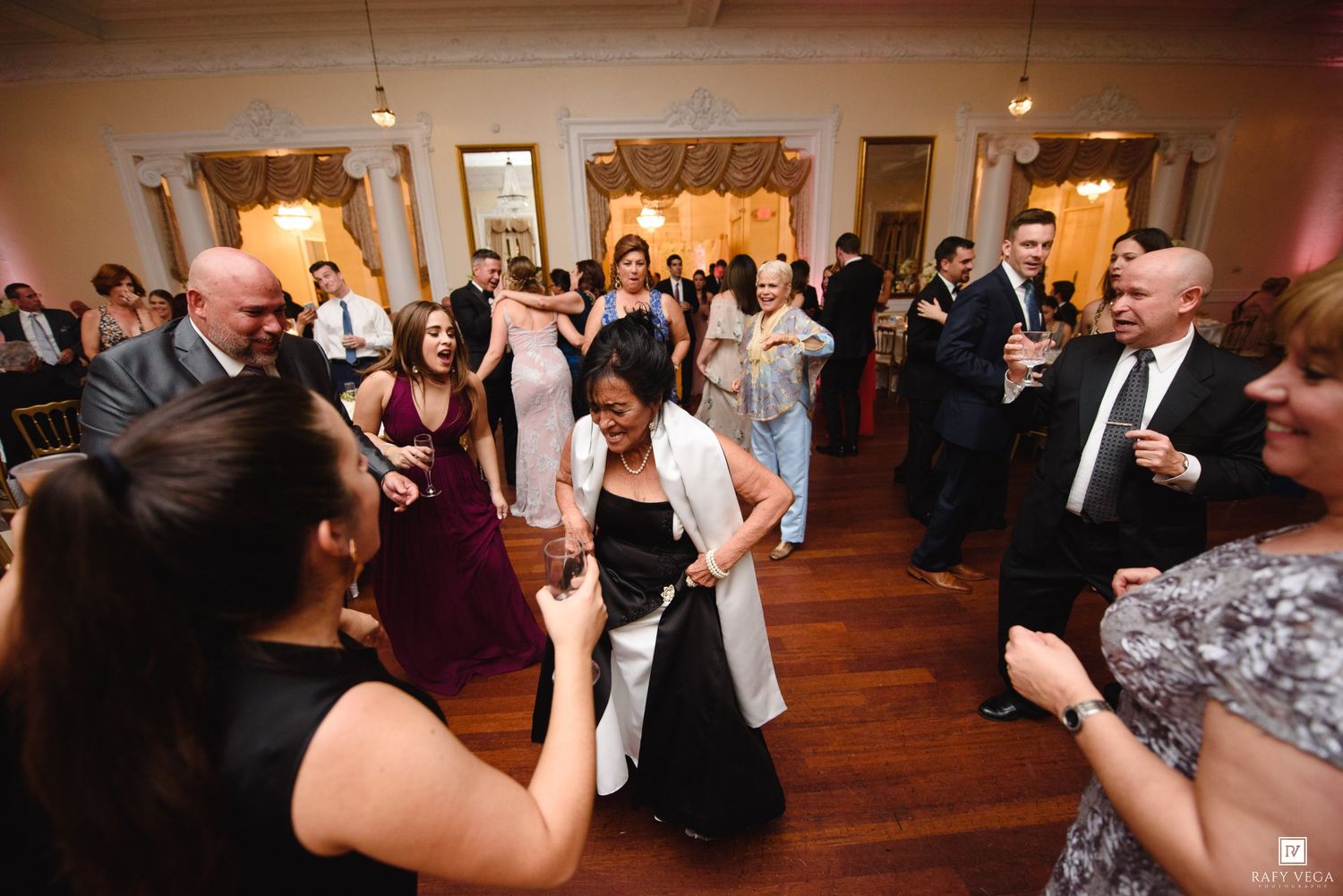 Guests dancing and celebrating at an elegant wedding reception on a hardwood dance floor.