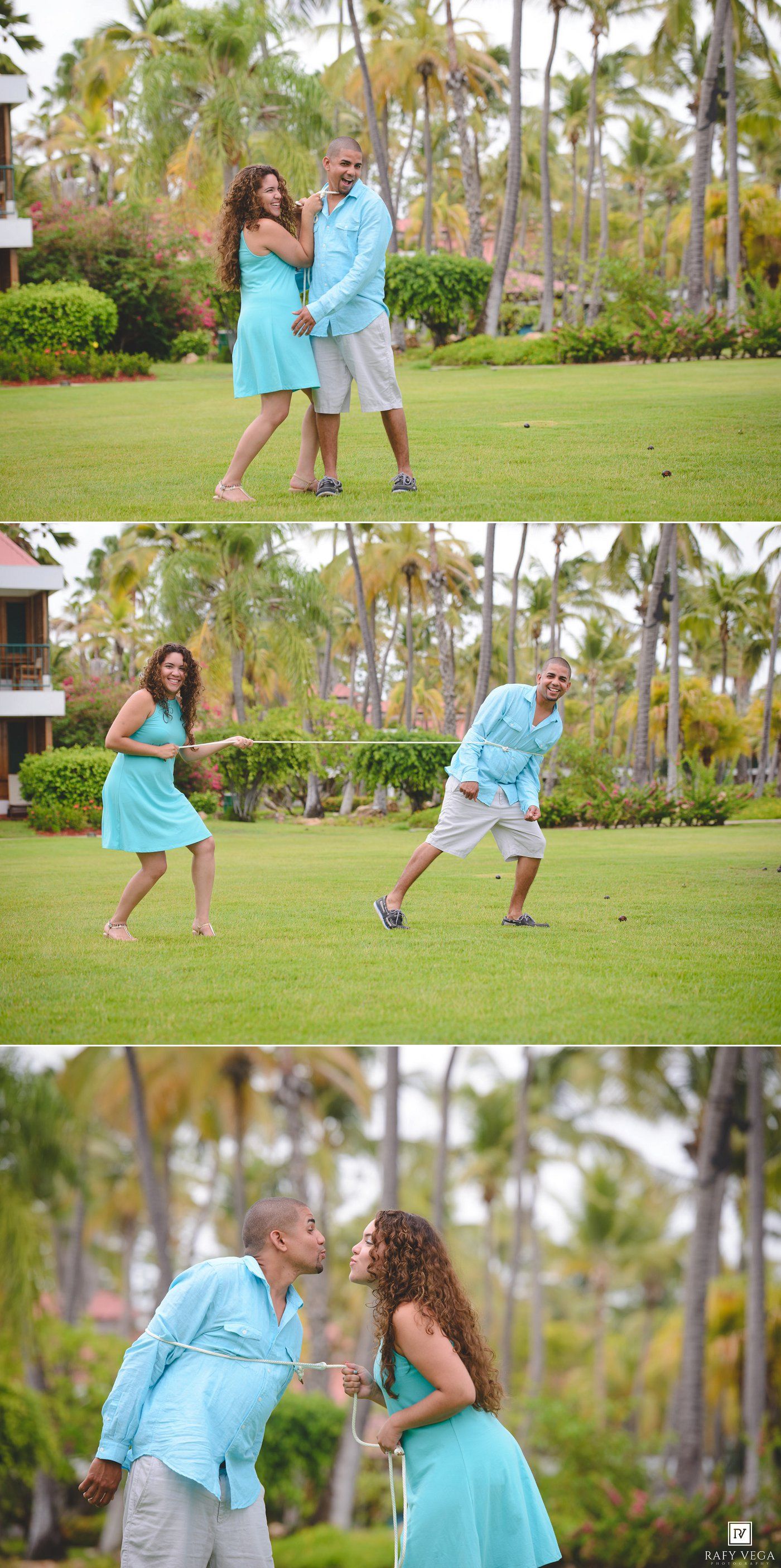 A playful couple in matching turquoise outfits laughs and dances on a tropical resort lawn.