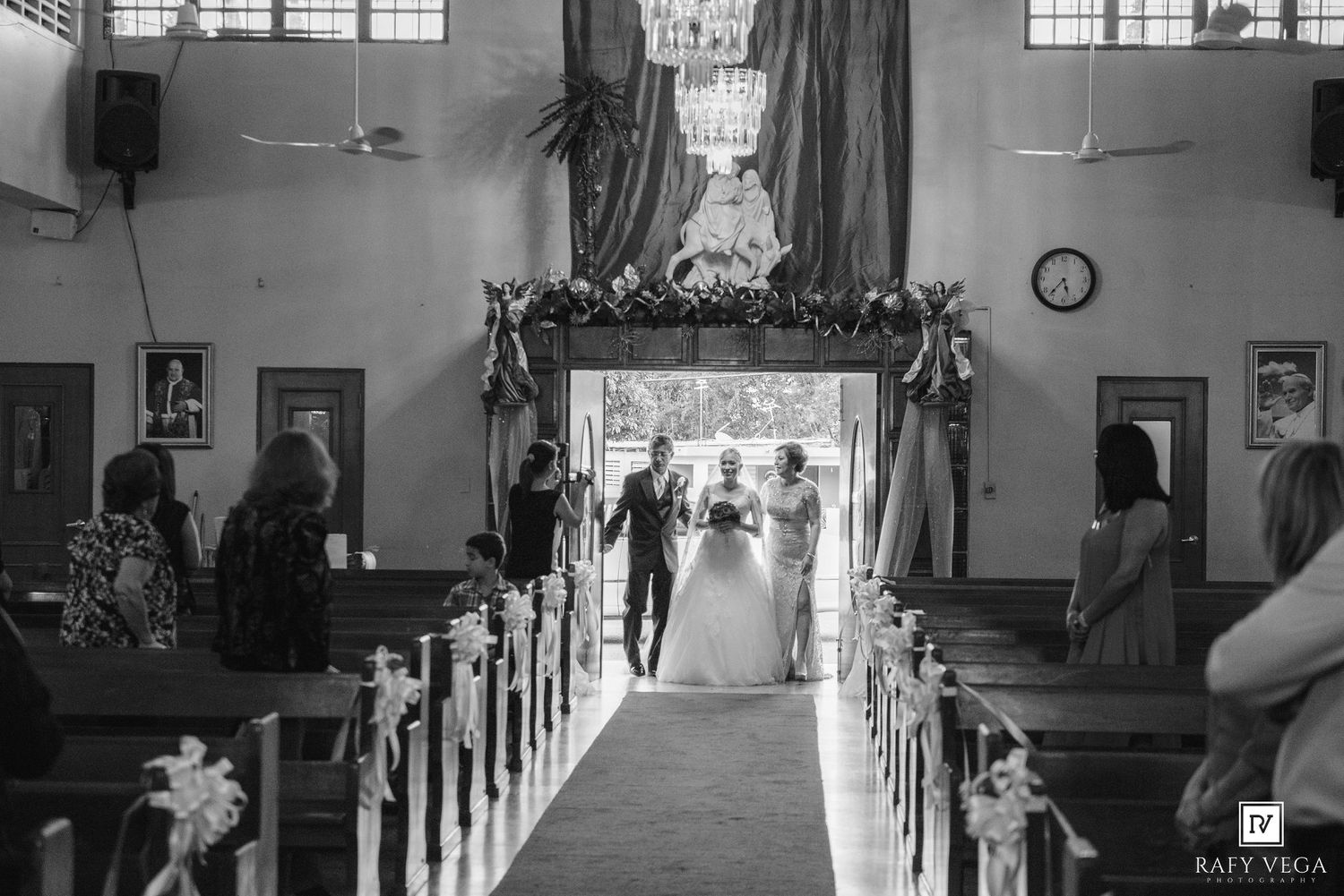 Black and white photo of a bride and groom walking down the aisle of a church after their wedding ceremony.