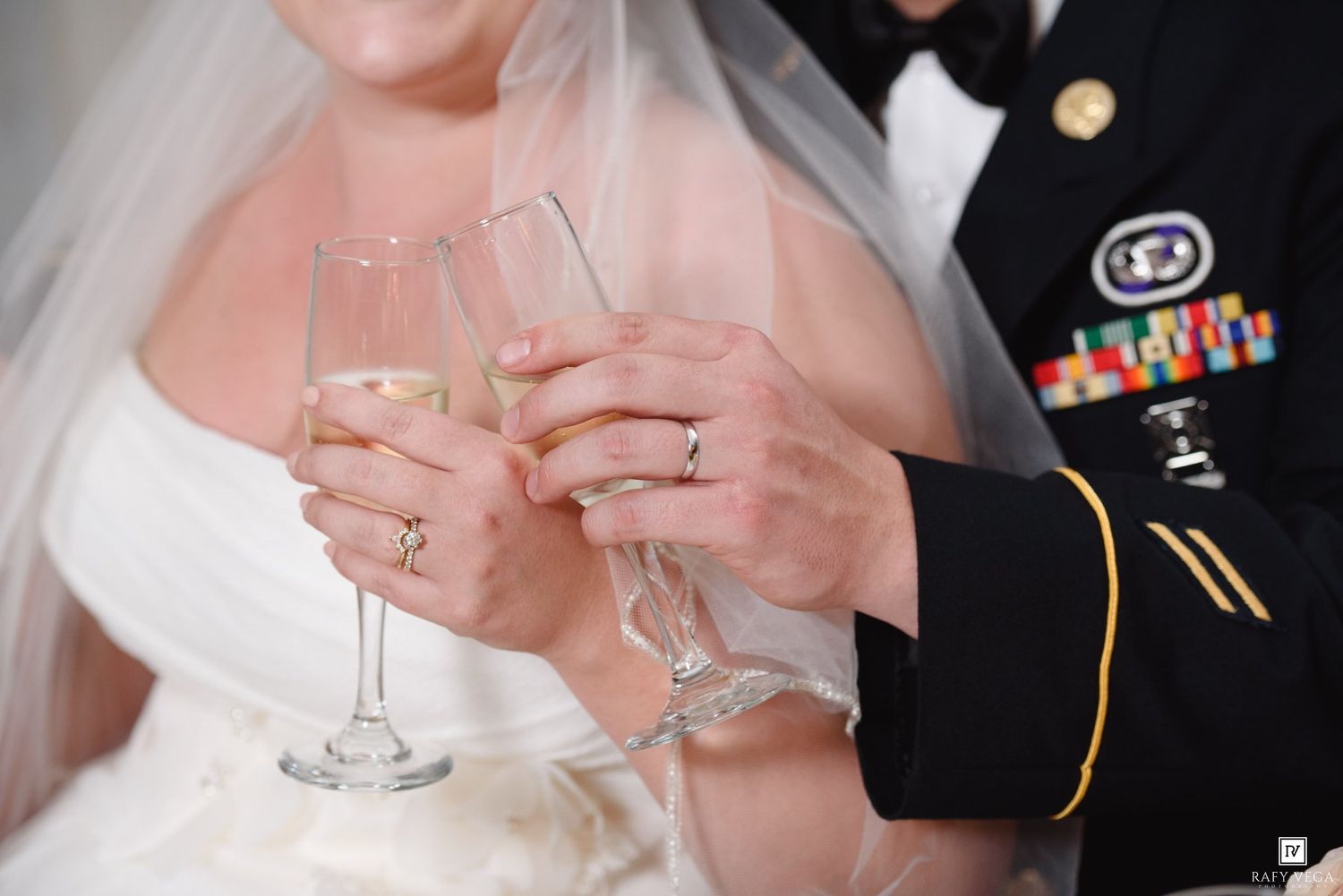 Bride and groom in military uniform toasting with champagne flutes at their wedding ceremony.