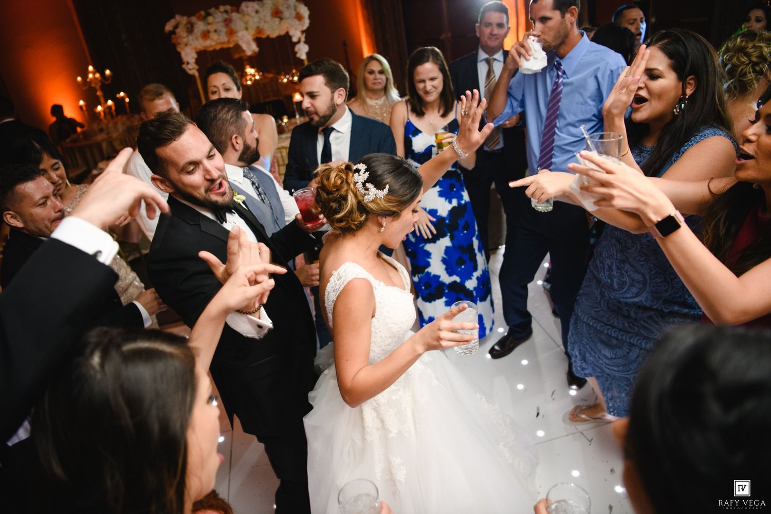 Bride and groom share a joyful dance surrounded by cheering guests at an elegant wedding reception.