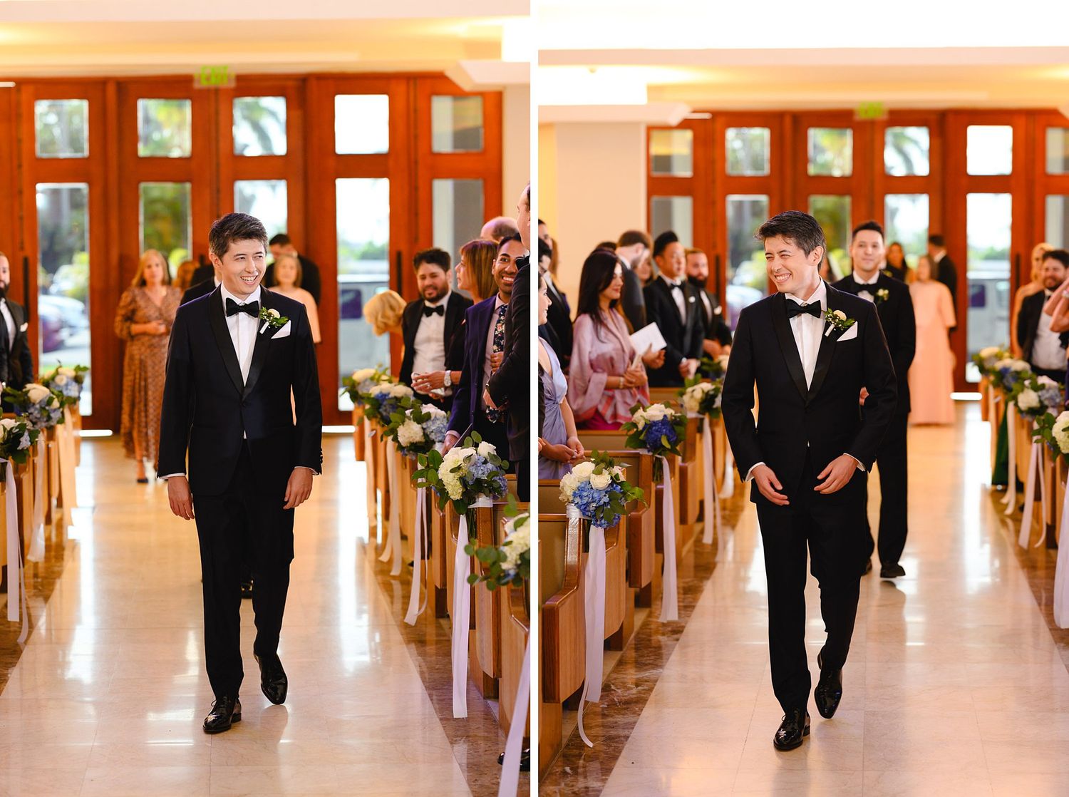 Groom in black tuxedo walks down church aisle lined with floral arrangements during wedding ceremony.