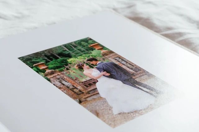Elegant wedding photo album open to a romantic image of bride and groom sharing a kiss outdoors.