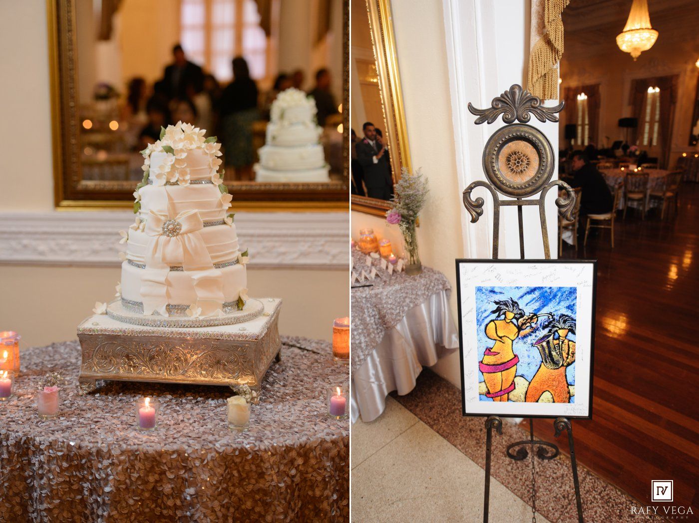 Elegant multi-tier white wedding cake on silver stand beside colorful artwork on easel in grand ballroom reception venue.