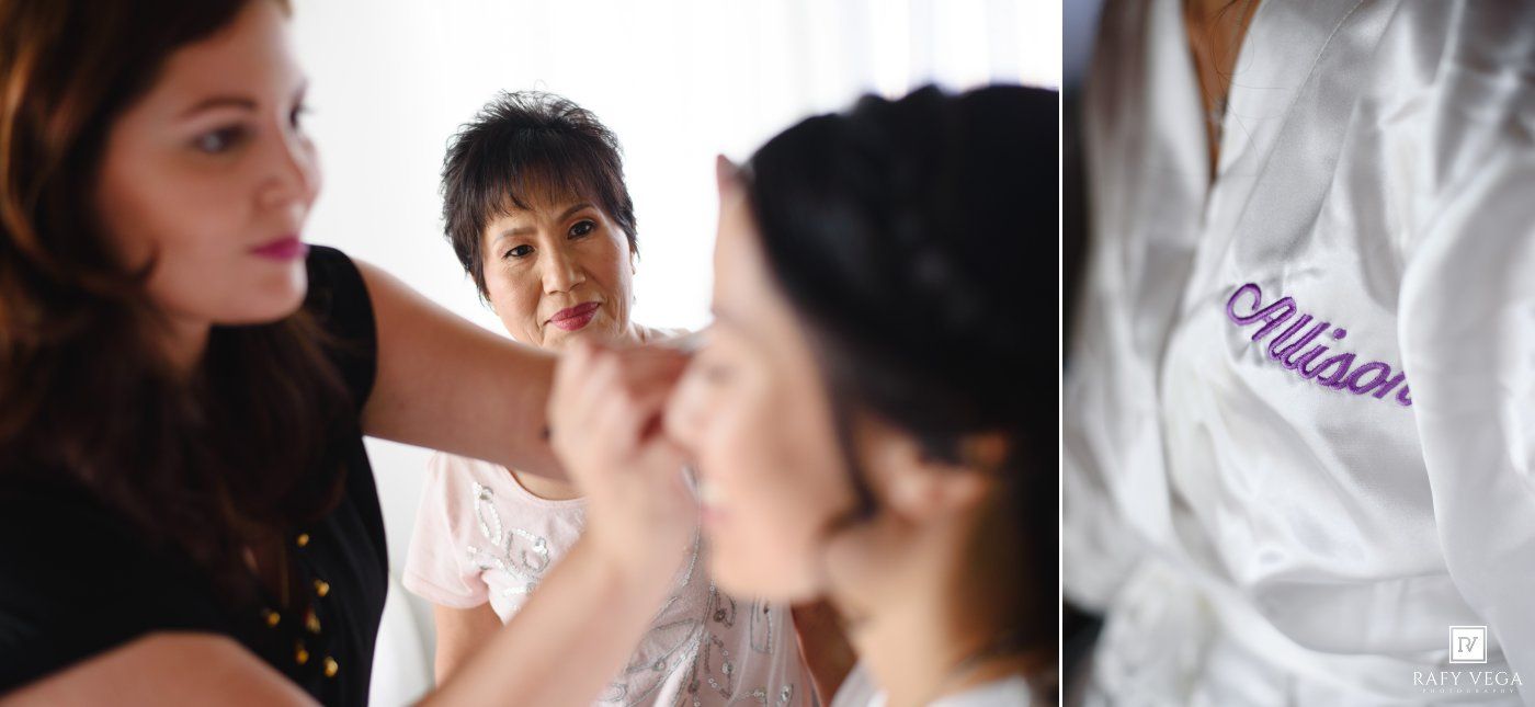 Bride getting makeup done by artist while woman in white robe with Allison embroidered watches in bright room.