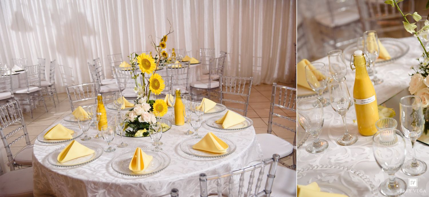 Elegant wedding reception table setting with yellow napkins, sunflowers, crystal glassware and yellow bottle centerpiece.